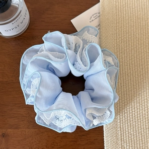 Gros plan sur un chouchou en maille bleu clair avec dentelle sur table en bois vintage