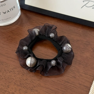 Elegant black mesh hair scrunchie with faux pearls on a wooden desk background
