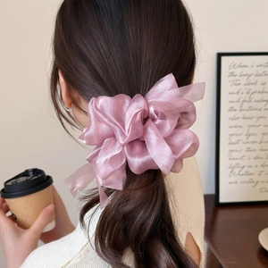 Detail of a sheer lavender organza bow scrunchie styled on a low ponytail hair tie
