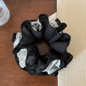 Détail de l'élastique multicouche en maille noire plissée et dentelle blanche fleurie