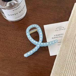 Détail d'une pince à cheveux bleu clair à pois blancs sur un fond de table en bois foncé