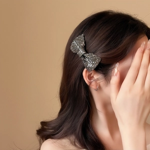 Detail einer eleganten Strass-Schleife-Haarklammer auf dunklem gewelltem Haar