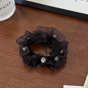 Detailed shot of black tulle scrunchie featuring sparkling rhinestones on dark wood