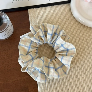 Detail eines gelb-blau karierten Haargummis mit flauschiger Textur auf Holztisch