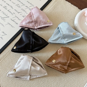 Close-up of satin fabric hair clips in five colors with round gold metal brand charms