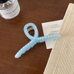 Détail d'une pince à cheveux bleu clair à pois blancs sur une table en bois foncé