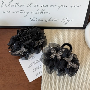 Close-up of black mesh flower hair claw clips with sparkling rhinestone butterfly details