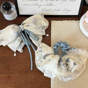 Floral print bow hair clip and matching scrunchie with pearls on a wooden desk