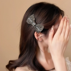 Eleganter Haarclip mit Strass-Schleife auf Modell mit funkelnden grauen und silbernen Kristallen