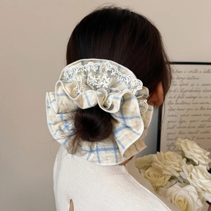 Blue and yellow plaid scrunchie with white lace trim shown on model hair bun
