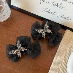 Detailed macro view of black mesh butterfly hair clips with shimmering rhinestone center