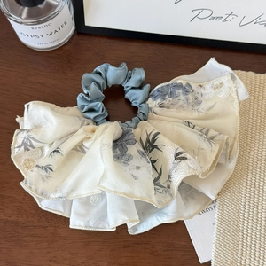 Detail of bamboo print silk scrunchie with lace embroidery on wooden background