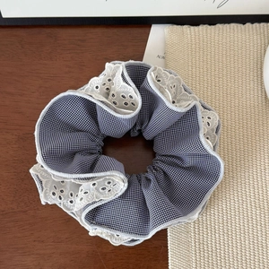 Detail of blue houndstooth hair scrunchie with white lace embroidery on wooden background