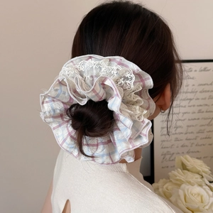 Pink and blue plaid scrunchie with white lace trim shown on model for hair styling