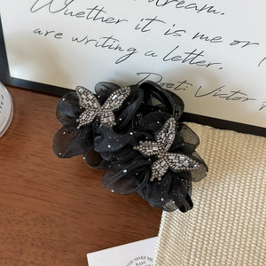 Detail of elegant black hair claw with mesh petals and rhinestone butterfly ornaments