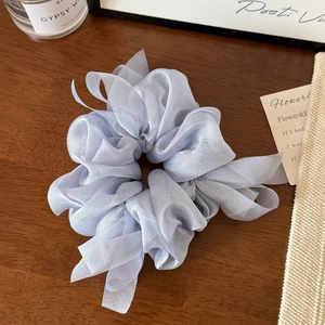 Detail shot of light purple organza scrunchie with soft mesh texture on wooden surface