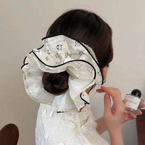 Scrunchie oversize crema con stampe di gatti neri e pizzo dorato su uno chignon