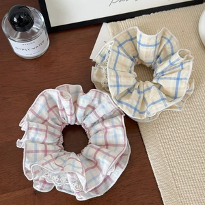Detail of red and yellow plaid scrunchies with white lace edges on a wooden surface