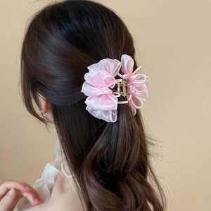 Dettaglio di un fermaglio per capelli con fiocco in rete rosa su un'acconciatura semi-raccolta
