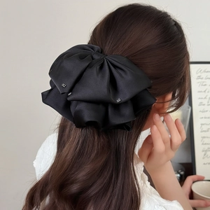 Elegant black satin multi-layer bow hair claw clip with rhinestones worn by a model