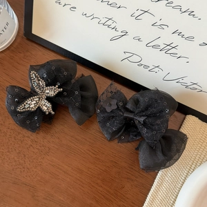 Close-up of black lace bow hair clip with sparkling rhinestone butterfly detail
