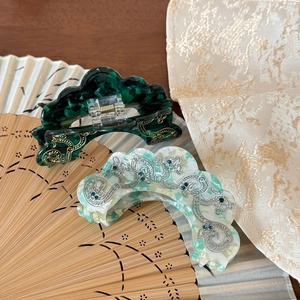 Détail des pinces à cheveux dragon chinois en acétate marbré vert et finitions dorées