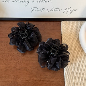 Dettaglio macro delle mollette per capelli a fiori in chiffon nero con glitter