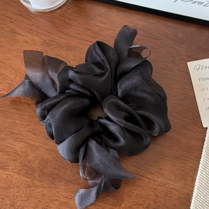 Detail of elegant black ribbon scrunchie with silky satin and translucent tulle fabric textures