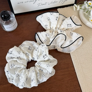Eleganti elastici scrunchie color crema con stampa gatto e bordi increspati su sfondo decorato