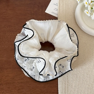 Dettaglio dell'elastico scrunchie in chiffon crema con stampe di gatti e pizzo
