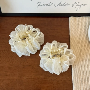 Dettaglio di eleganti mollette per capelli a fiori in organza bianco crema a strati