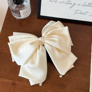 Dettaglio del grande fiocco in raso color crema con ciondoli in cristallo su legno