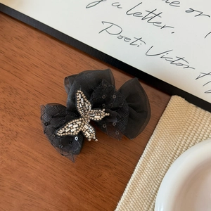 Detail of a black tulle bow hair claw clip featuring a vintage rhinestone butterfly ornament