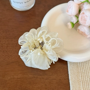 Dettaglio di un fermaglio per capelli floreale in tessuto di organza bianco crema