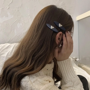 Détail de deux pinces à cheveux ovales en acétate bleu foncé avec strass en forme de cœur