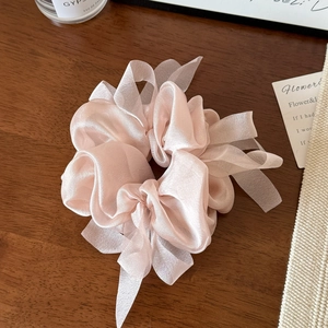 Detailed close-up of a soft pink ribbon scrunchie with silk-like fabric texture