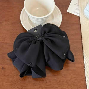 Detail of elegant black bow hair claw with silver rhinestones on a wooden background