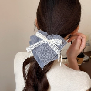Blue plaid scrunchie with white lace trim and ribbon bow on model's ponytail