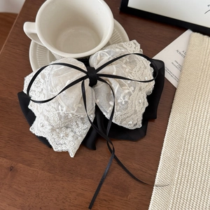 Detail of lace bow hair clip with pearls and black ribbon on a wooden table