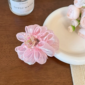 Dettaglio ravvicinato di una molletta per capelli a fiore in organza rosa cipria