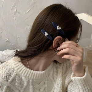 Détail de barrettes en acétate bleu marine avec cœurs en strass argentés sur les cheveux