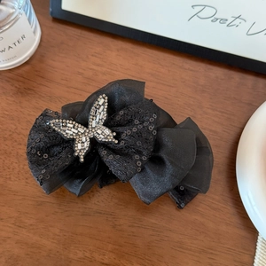 Detailed close-up of a black lace butterfly hair claw with sequins and a rhinestone center