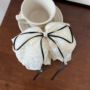Vue détaillée du nœud en dentelle crème avec ruban noir et perles de cristal brillantes