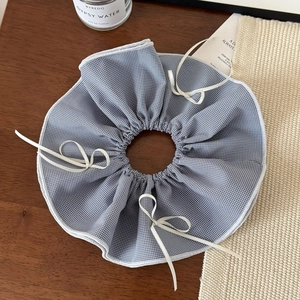 Detail of blue and white checkered oversized scrunchie with delicate white ribbon bows