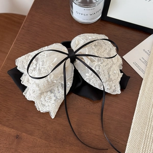 Detail of elegant lace bow hair clip with white pearls and delicate long ribbon tassels