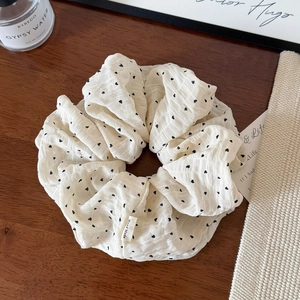 Detail of white scrunchie with black heart pattern and Hand Made woven label