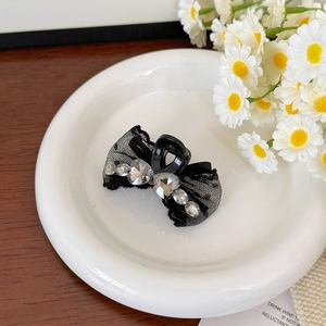 Détail d'une pince à cheveux en dentelle noire avec cristal en cœur sur une assiette