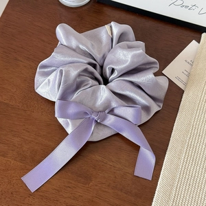 Détail du chouchou en satin violet avec nœud élégant sur une surface en bois