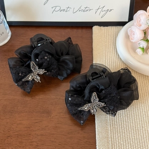 Detail of elegant black lace hair claw clip with sparkling silver rhinestone butterfly