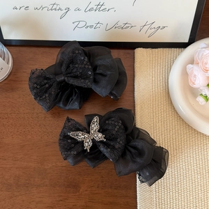Elegant black organza butterfly hair clips with sequins and rhinestones on a table